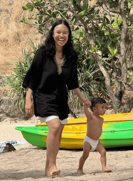 A woman and child walking beside colorful kayaks