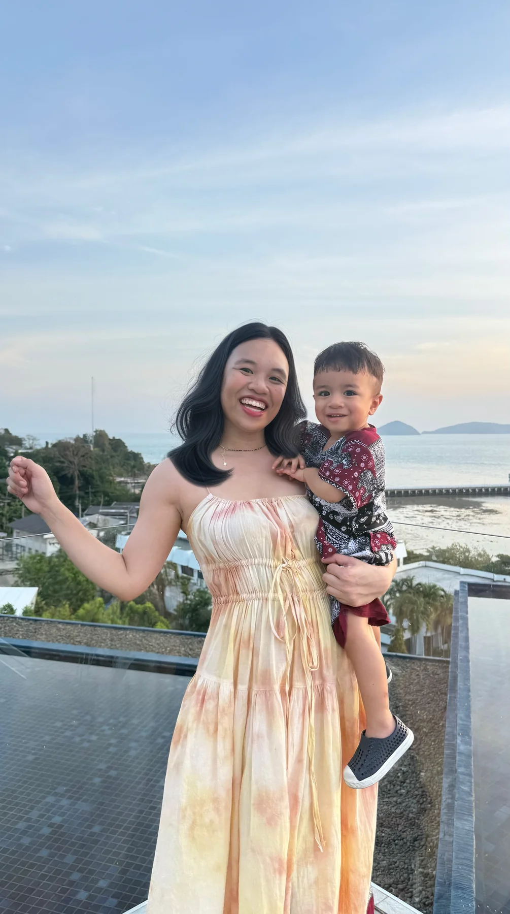 A mother holding her child on a terrace overlooking the sea