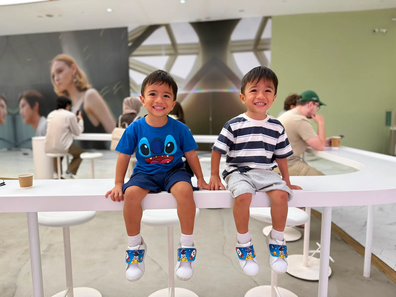 Two smiling children sitting side by side on a white counter